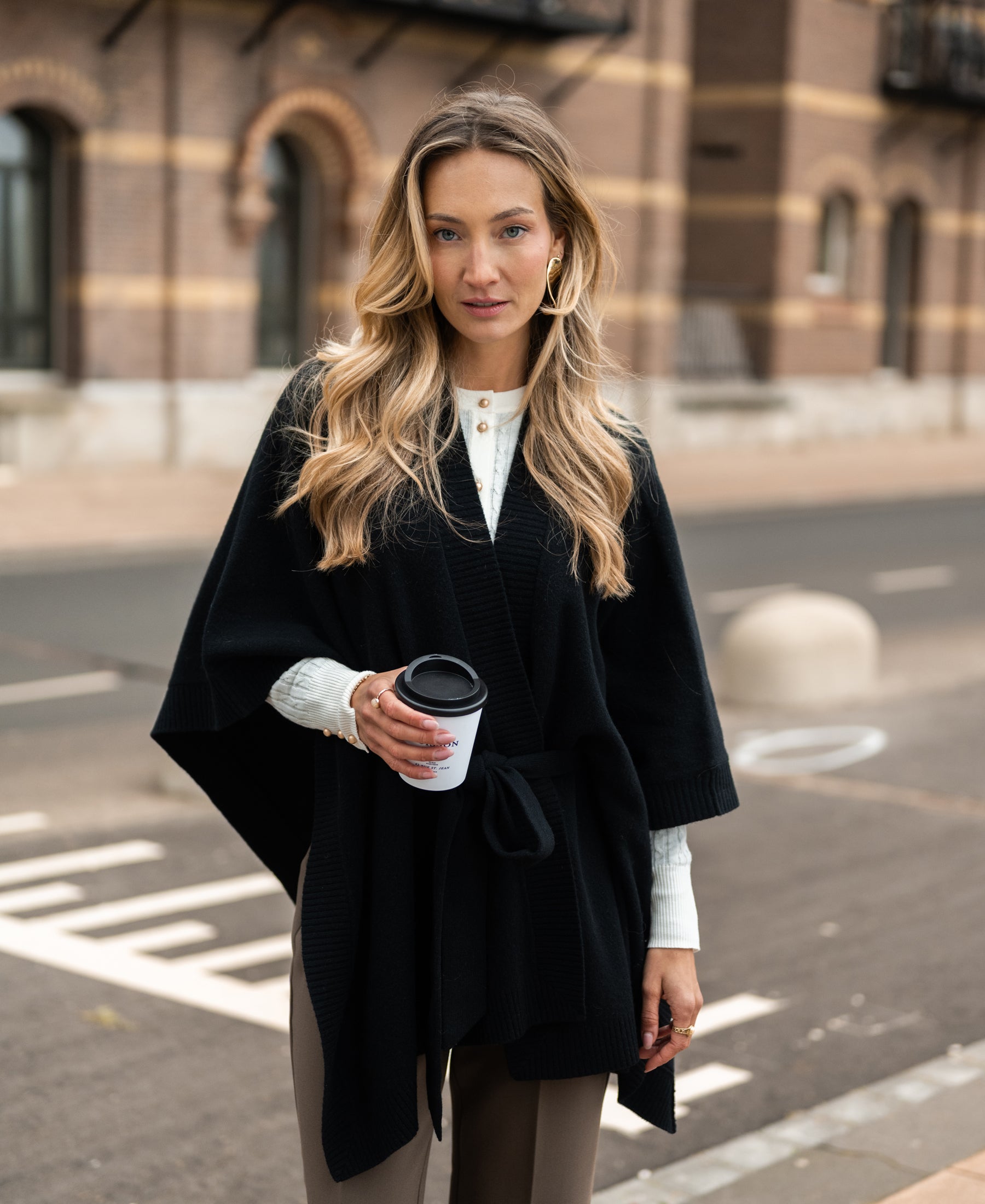 Black merino wool poncho shown outdoors.