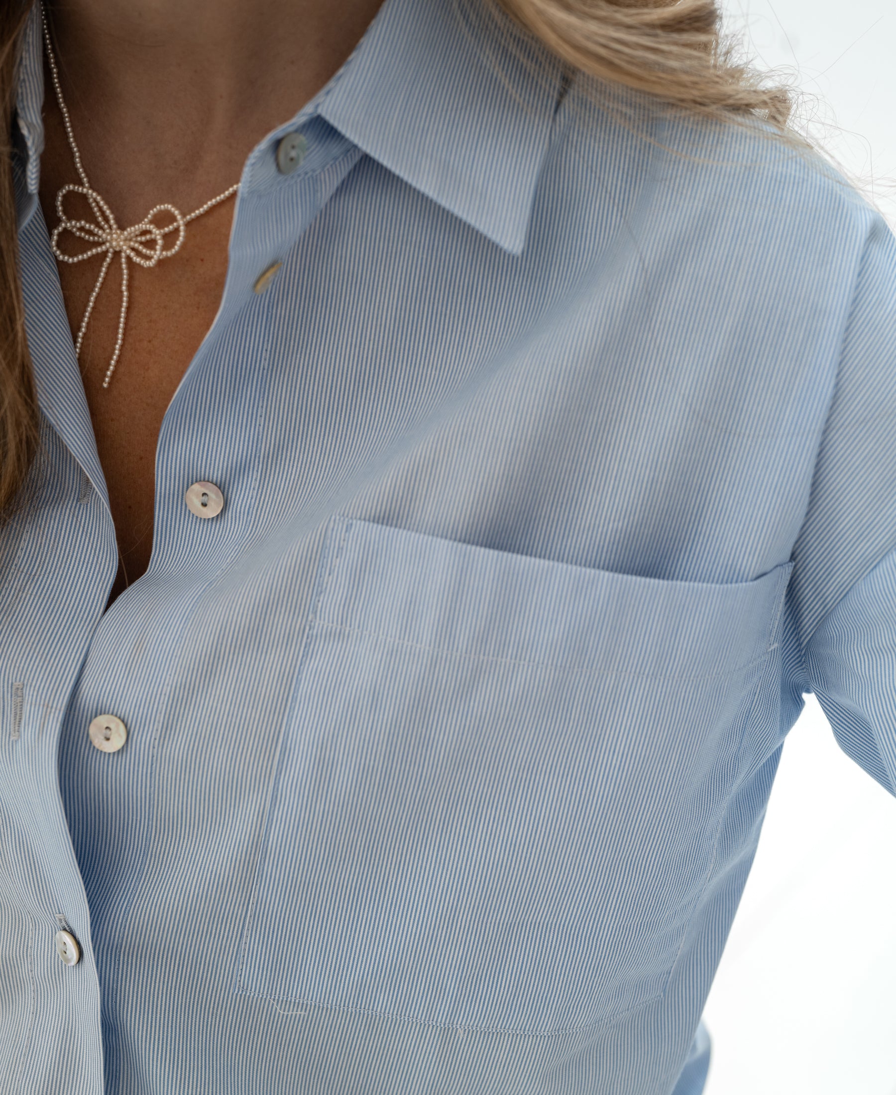 Woman wearing PLEIN PUBLIQUE LA PASCALLE light blue striped blouse.