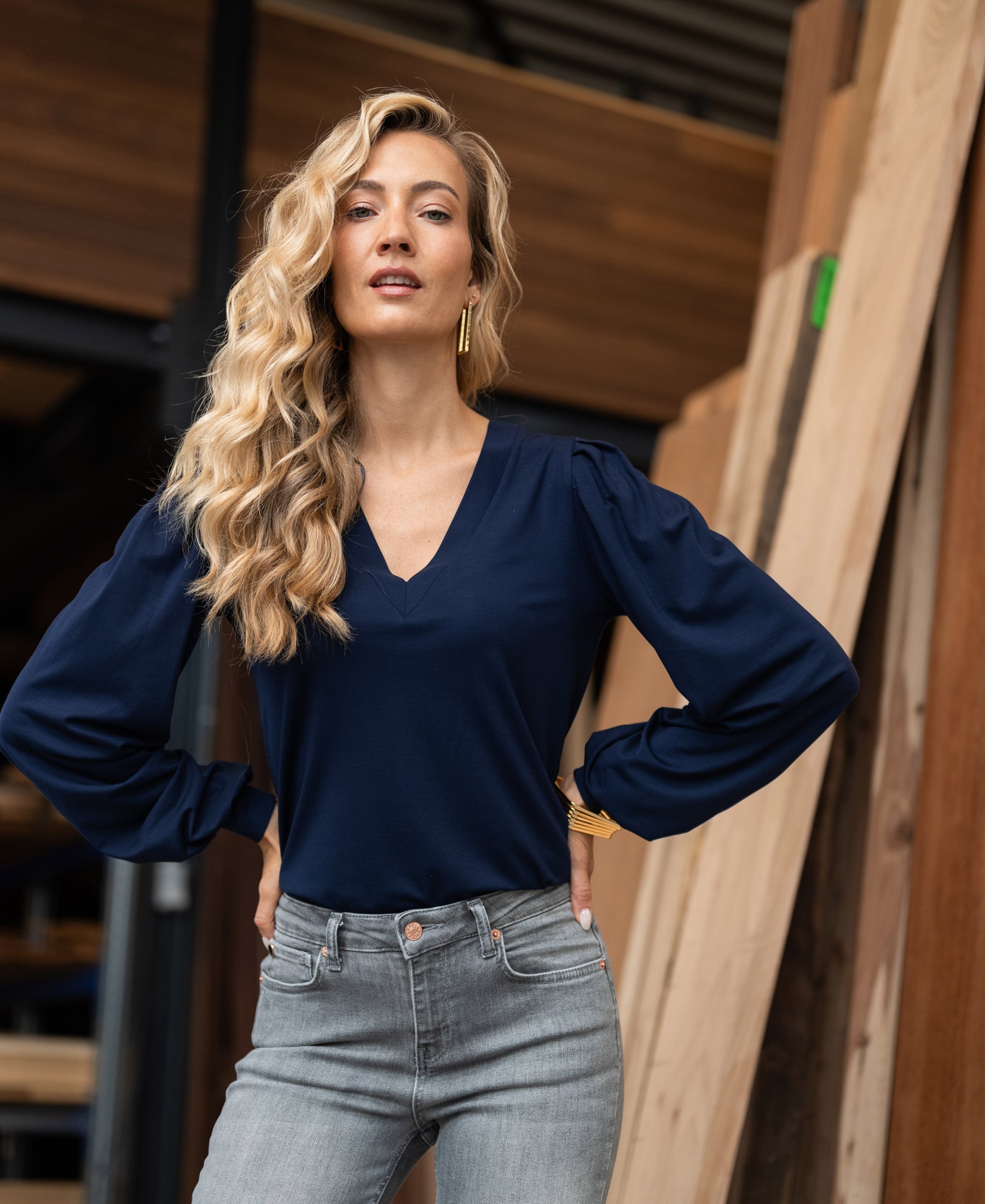 Woman wearing a navy blue PLEIN PUBLIQUE LA LIANA V-neck top, hands on hips.