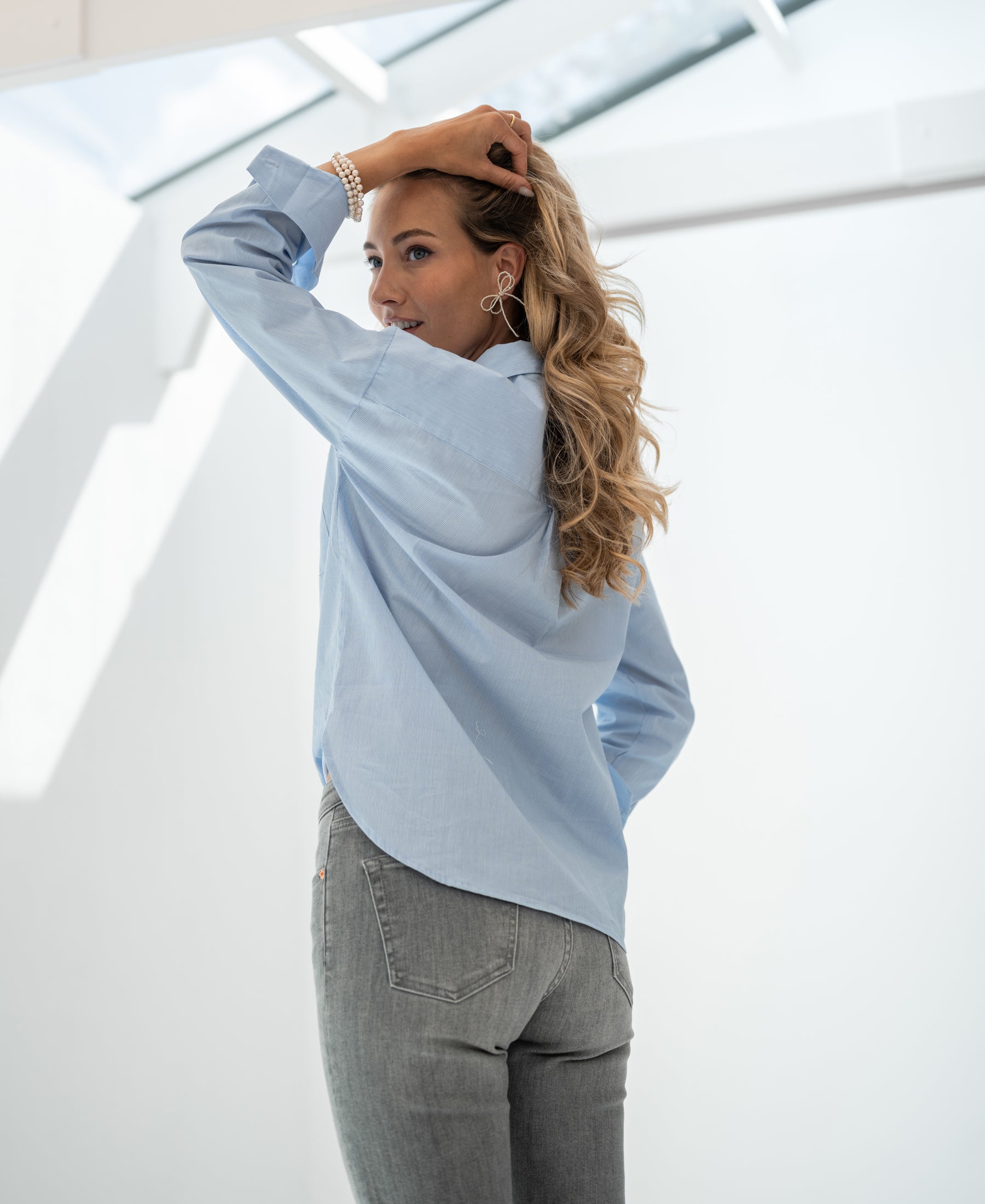 Light blue striped LA PASCALLE blouse by PLEIN PUBLIQUE shown indoors.