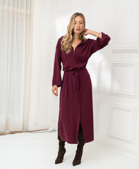 Woman wearing a Bordeaux LE RAPHAEL button-front dress with tie waist by PLEIN PUBLIQUE, standing indoors.