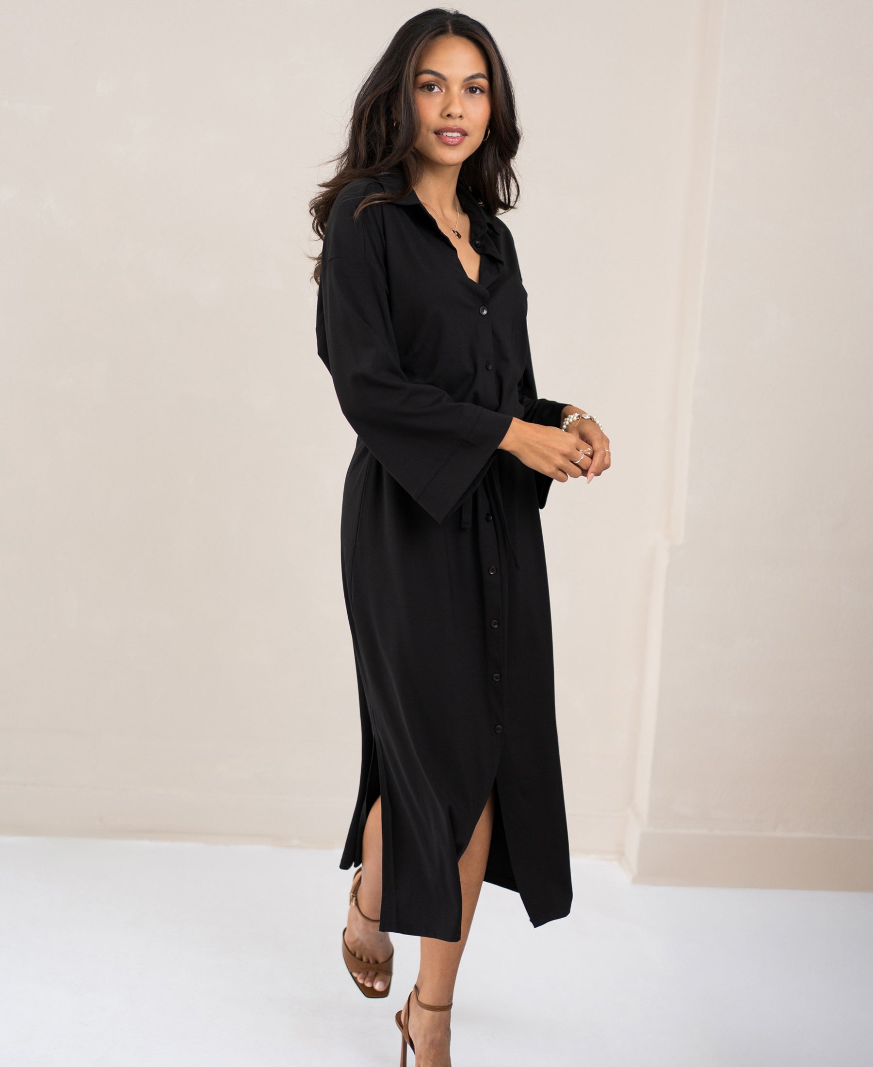 Black button-down dress by PLEIN PUBLIQUE displayed in a minimal, light-toned room.