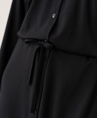 Close-up of the LE RAPHAEL Black Button-Front Dress by PLEIN PUBLIQUE, showing smooth fabric and a waist tie.