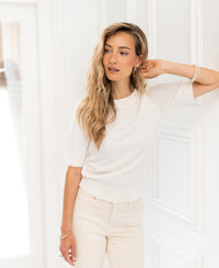 White knit LA REVE sweater by PLEIN PUBLIQUE displayed against a white paneled wall.