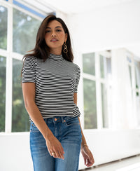 White and black ribbed collar top LA RIXY by PLEIN PUBLIC, shown indoors near large windows.