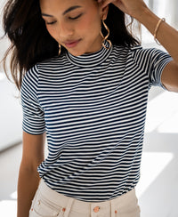 Woman wears PLEIN PUBLIQUE ribbed collar top LA RIXY in white-navy blue indoors.