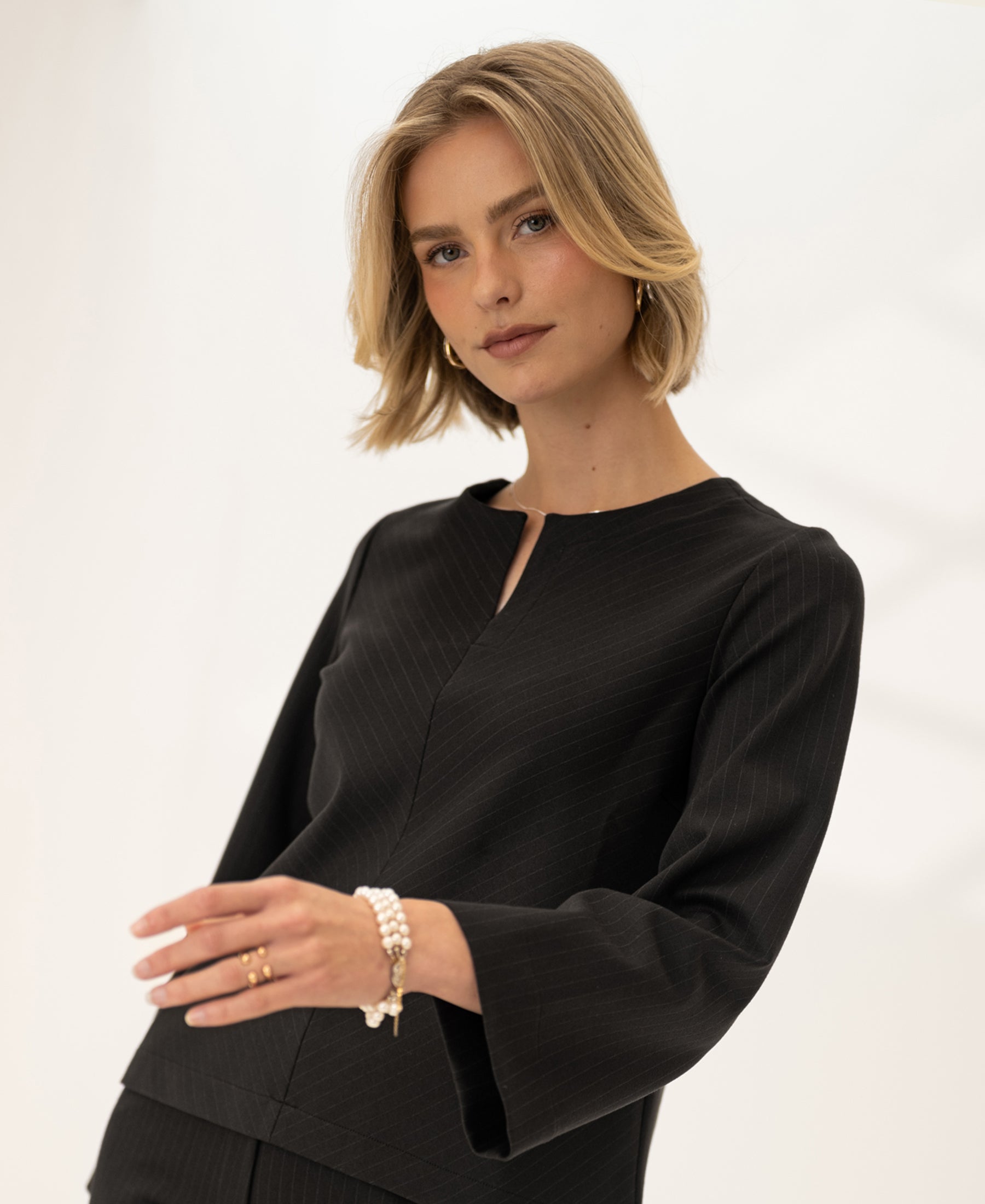 Woman wearing a striped top in pure chocolate color with 7/8 sleeves, shown against a soft backdrop.
