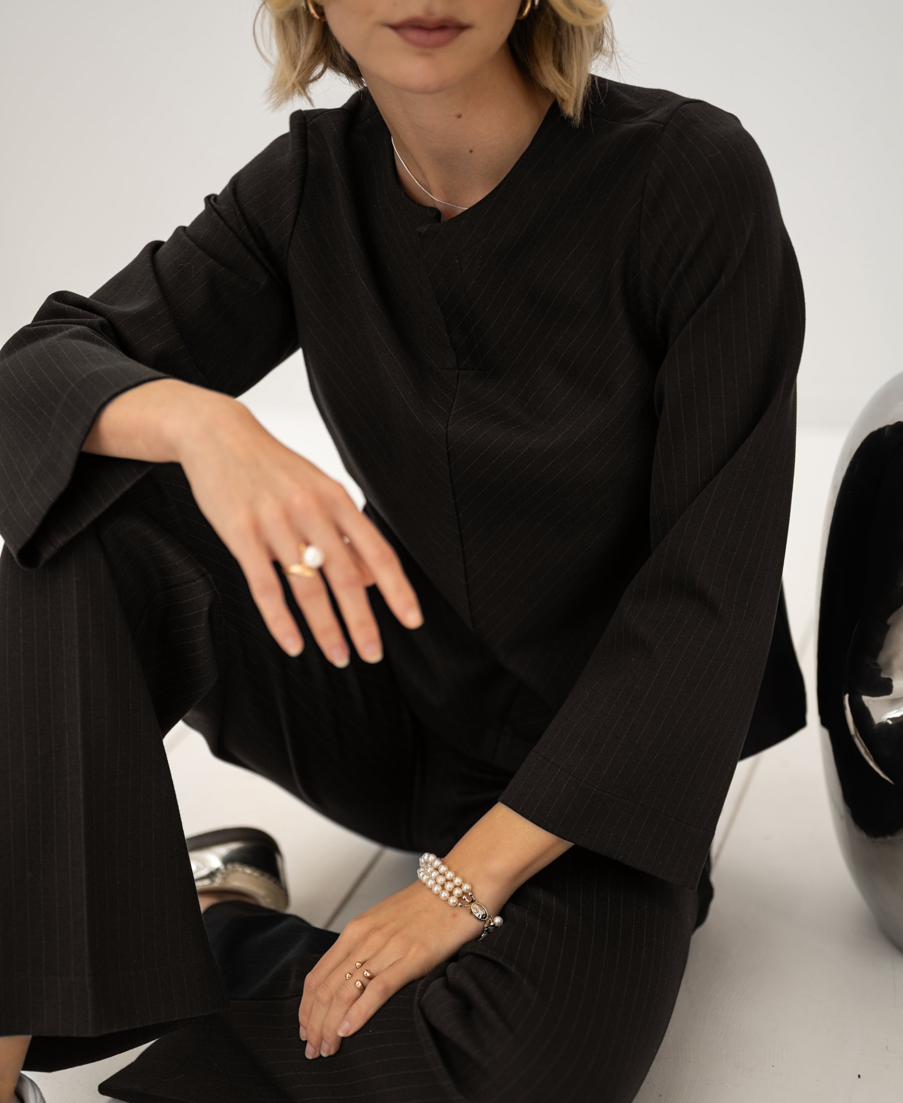 A woman wears the PLEIN PUBLIQUE pinstripe top in pure chocolate brown.