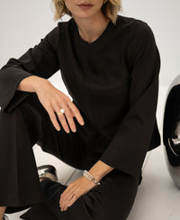 A woman wears the PLEIN PUBLIQUE pinstripe top in pure chocolate brown.