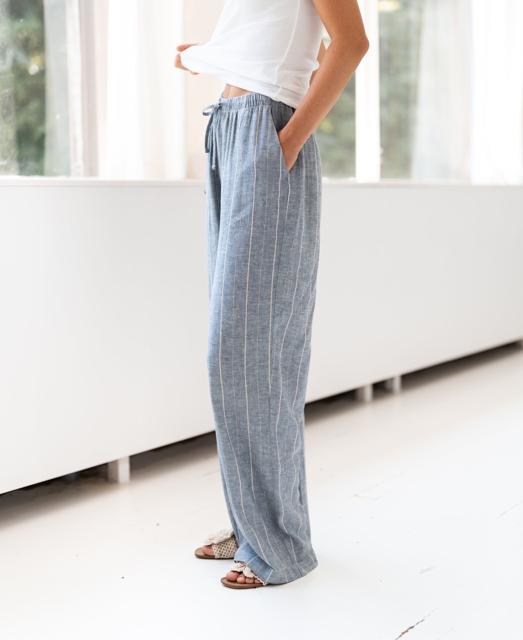 Gestreepte linnenblend broek LA SECONDE van PLEIN PUBLIQUE, getoond in een zonnig, licht interieur.