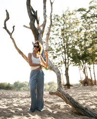 Striped linen-blend trousers in jeans blue by PLEIN PUBLIQUE, shown on sandy ground.