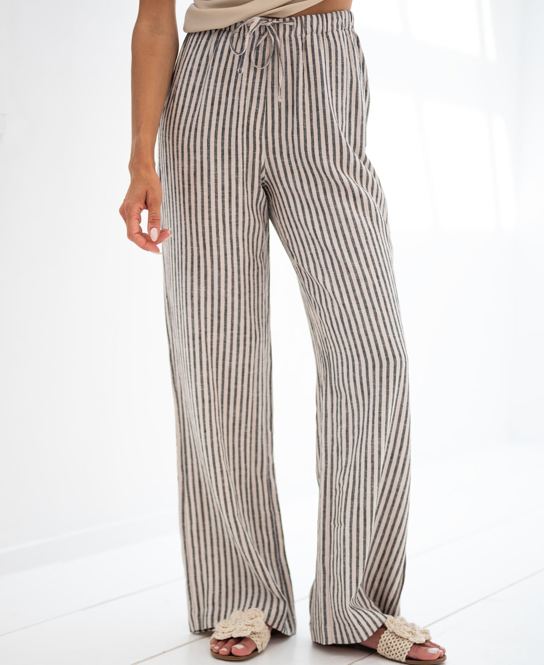 Person wearing striped linen-blend trousers in anthracite with black stripes, shown indoors.