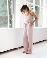 Light pink striped linen-blend pants, model standing by a sunlit window.