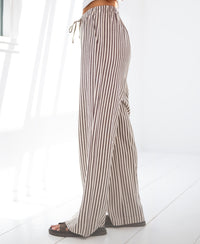 Striped brown linen-blend pants by PLEIN PUBLIQUE shown in a bright, sunlit room.