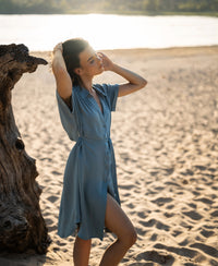 Cupro LA SELENE dress in Denim Cloud by Plein Publique shown outdoors with sunlight glowing behind.