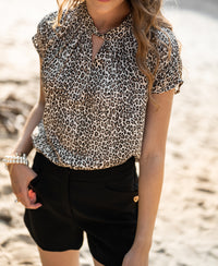Blouse top with leopard print from PLEIN PUBLIQUE, shown outdoors on a sunny, sandy path.