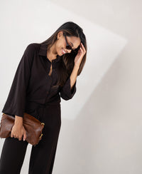 Woman wearing a brown Pure Choco LA SILVESE travel blouse, smiling and adjusting sunglasses.