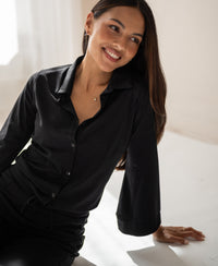 Woman with long dark hair wears the PLEIN PUBLIQUE black LA SILVESE travel blouse.