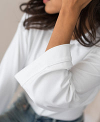 Woman wearing a white PLEIN PUBLIQUE LA SILVESE travel blouse with kimono sleeves.