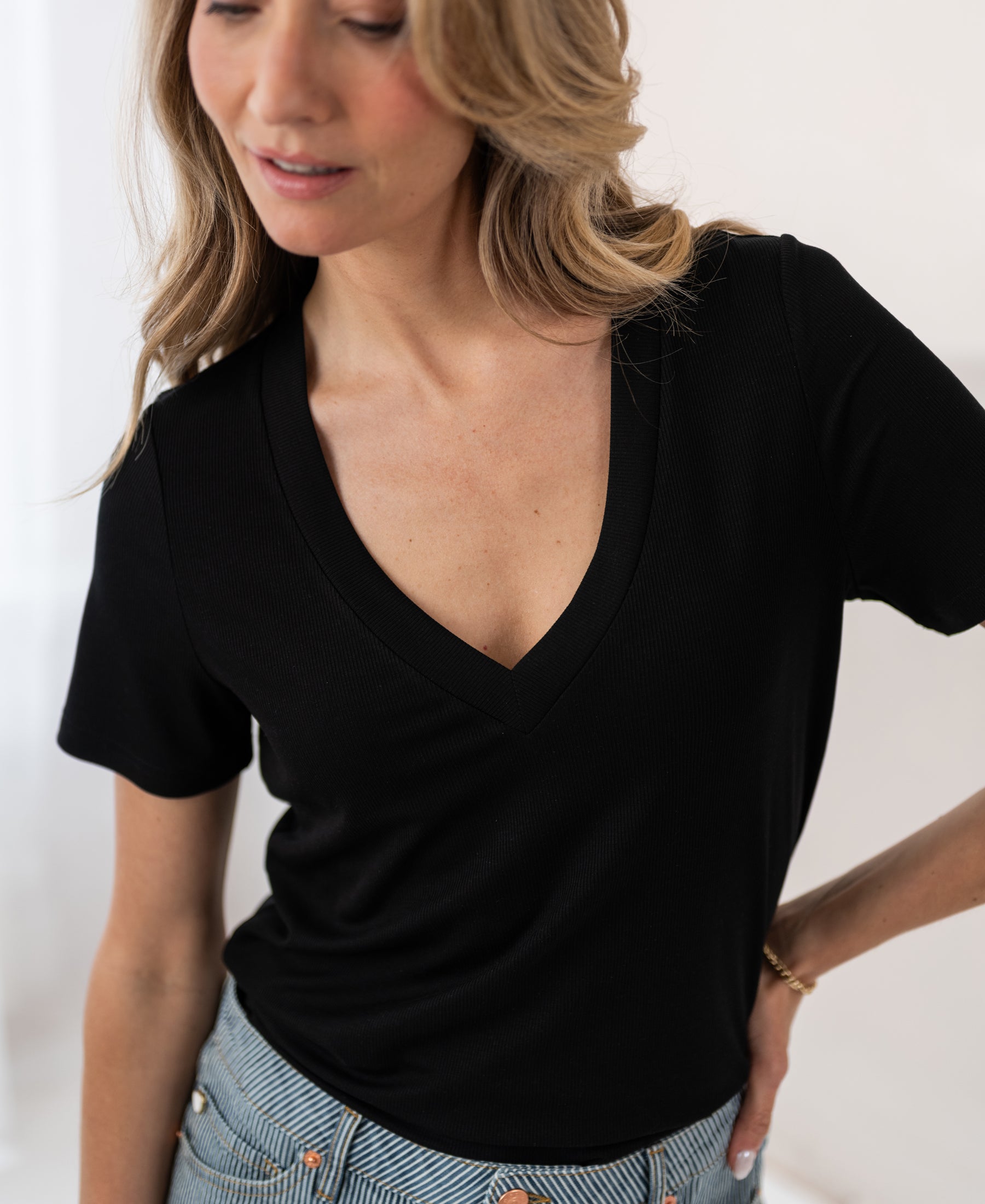 Black Lyocell T-shirt by PLEIN PUBLIQUE, front view, model looking down and smiling softly.