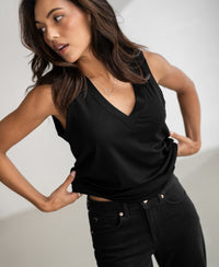 Woman wears a black PLEIN PUBLIQUE Lyocell top, posing indoors with hand on waist.