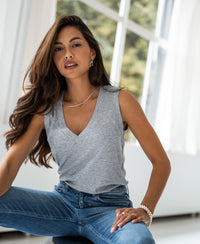 Woman wearing a grey melange Lyocell top sits by a bright window, facing the camera.