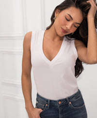 Woman wears a white Lyocell top against a white background.