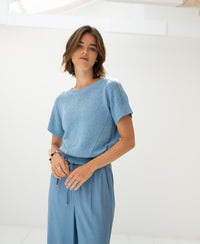 Light blue linen summer sweater displayed in a bright, minimal indoor space.