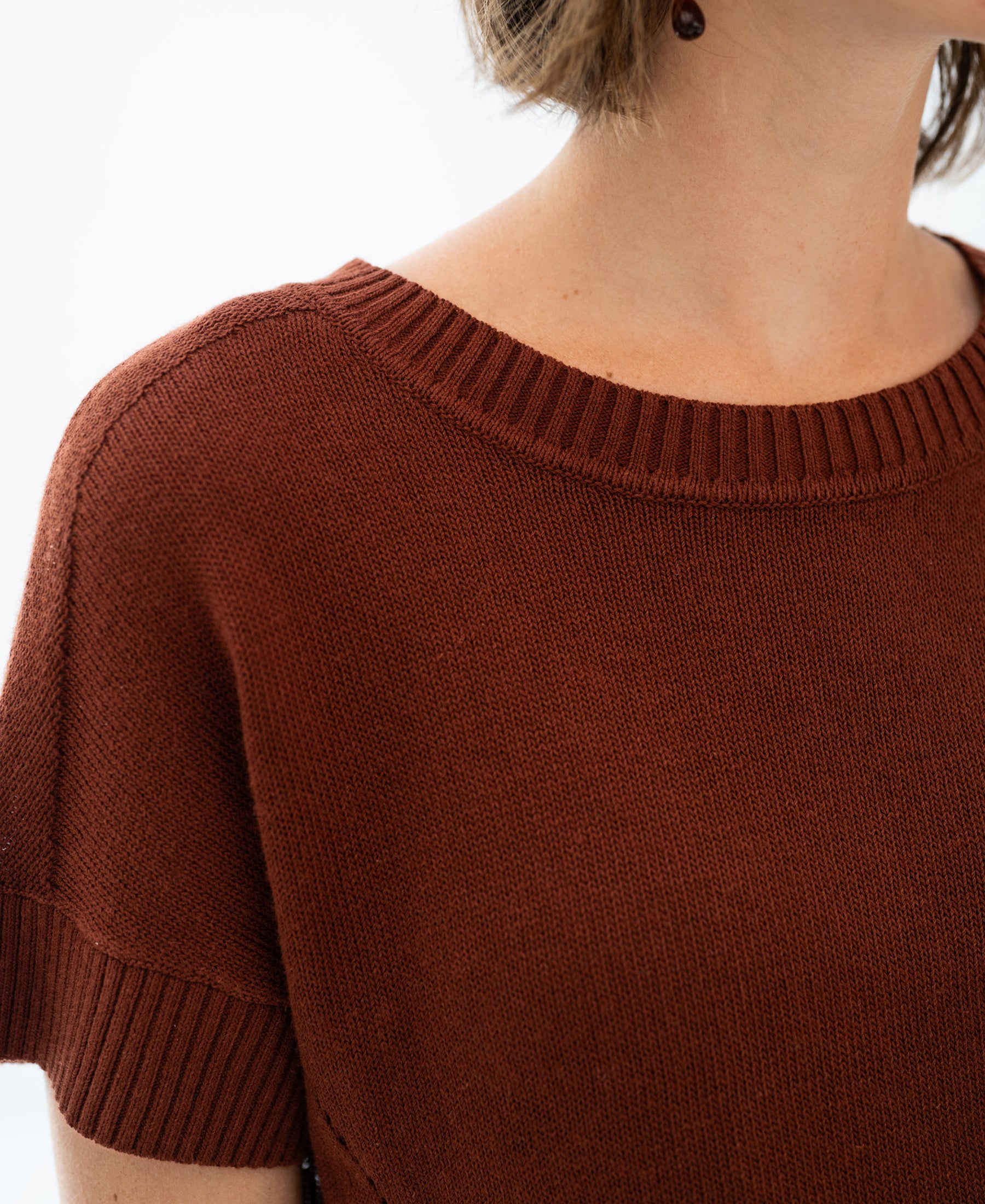 Close-up of a short-sleeved, rust-colored linen summer sweater.