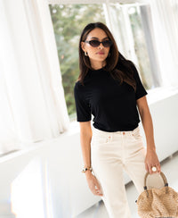 Woman wearing black bamboo turtleneck top in a bright room.