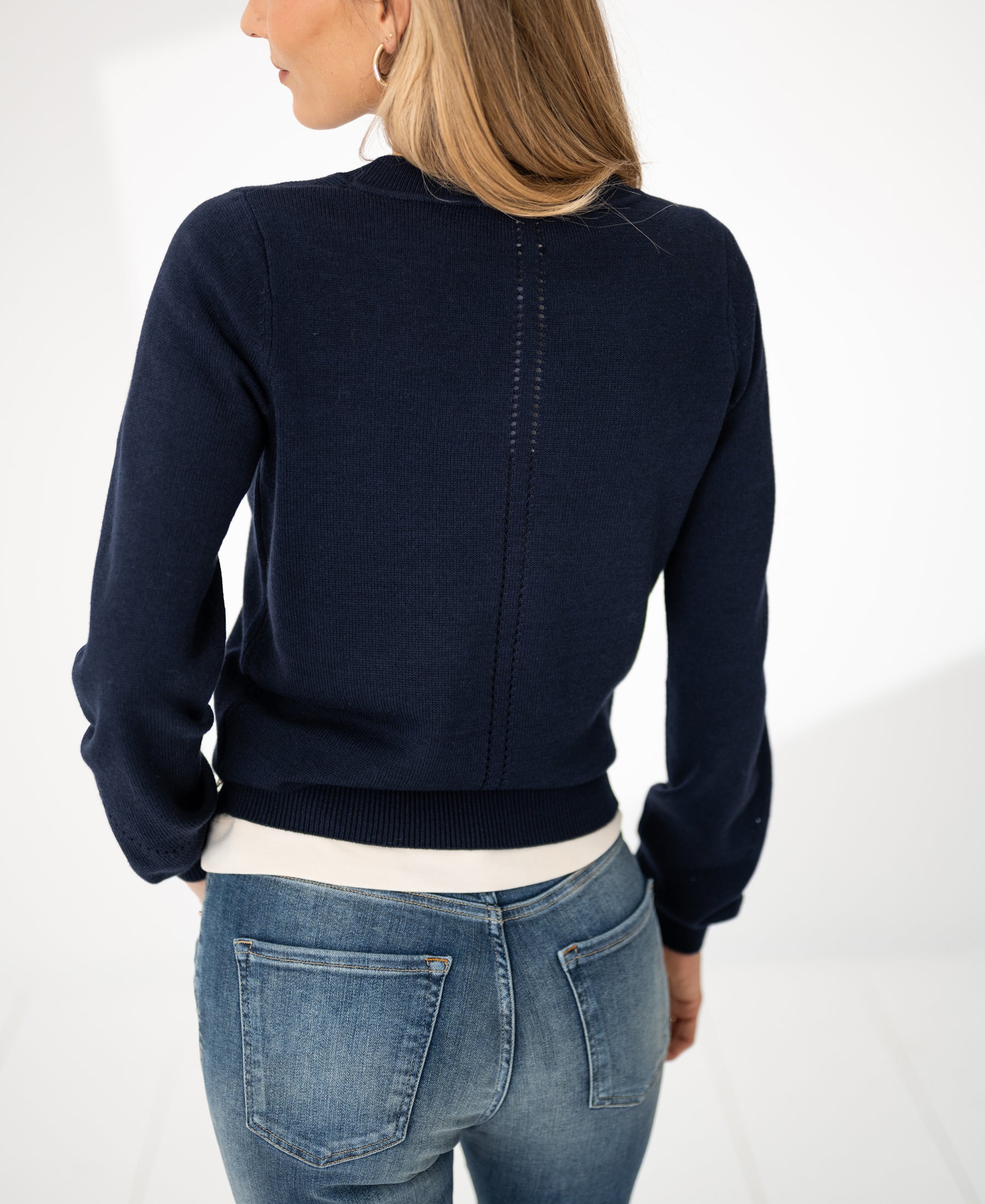 Back view of a woman wearing a PLEIN PUBLIQUE Merino blend sweater LE SONGE in navy, shown in a bright room.