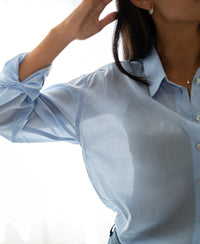 Light blue Dunne oversized blouse in silk, shown on a woman with one arm raised.