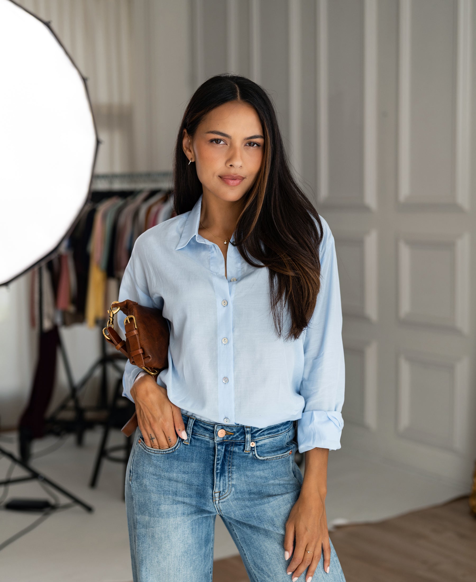 Woman wearing light blue silk oversized blouse indoors.