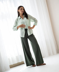 Woman poses indoors wearing a dark olive viscose mix PLEIN PUBLIQUE LA JULIA travel pant.