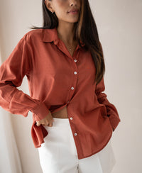 Woman wearing an oversized LA SOYEUSE Terra blouse in a neutral tone, posing indoors with one hand on her waist.