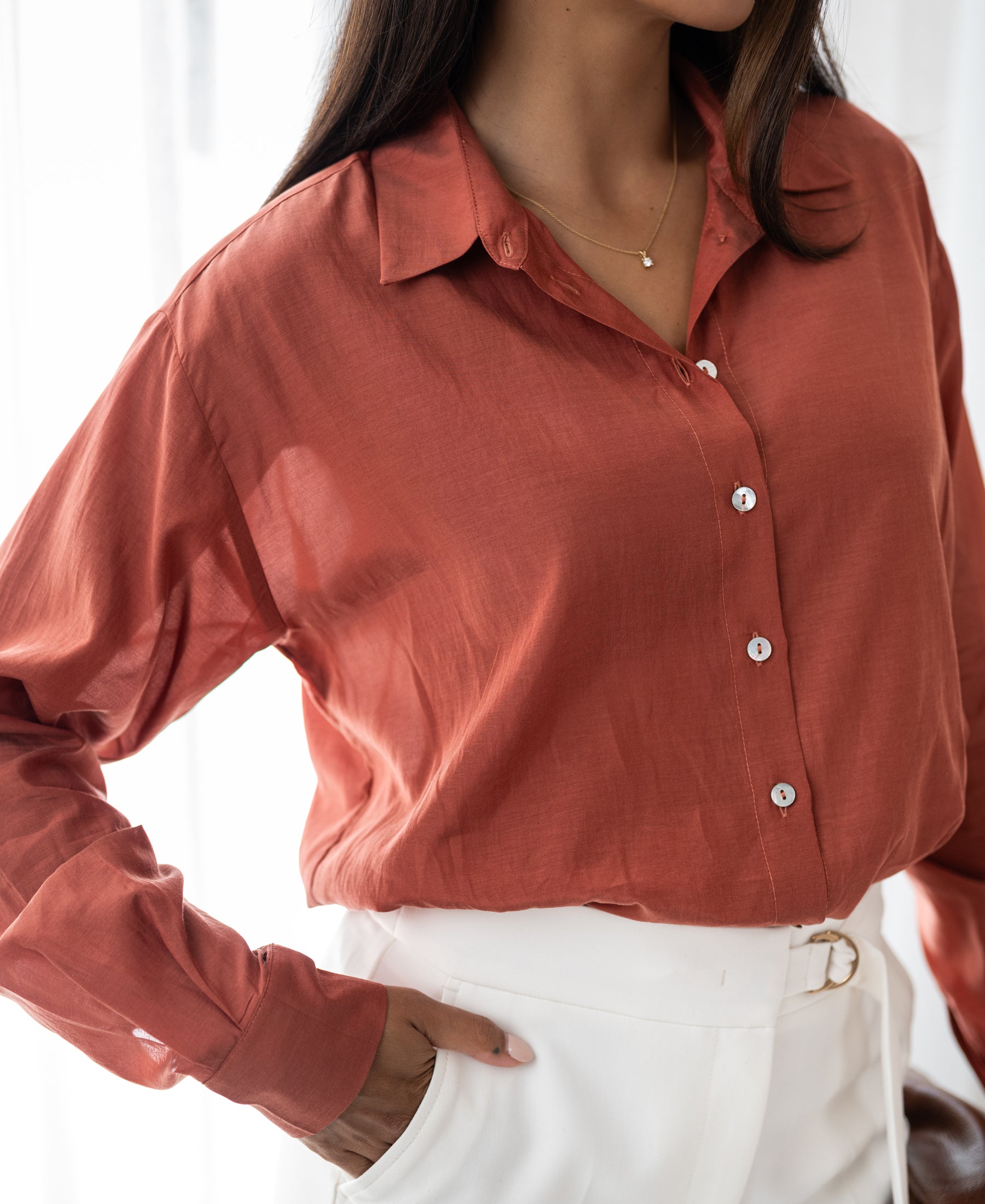 Woman wearing the Dunne oversized blouse in terra color silk.