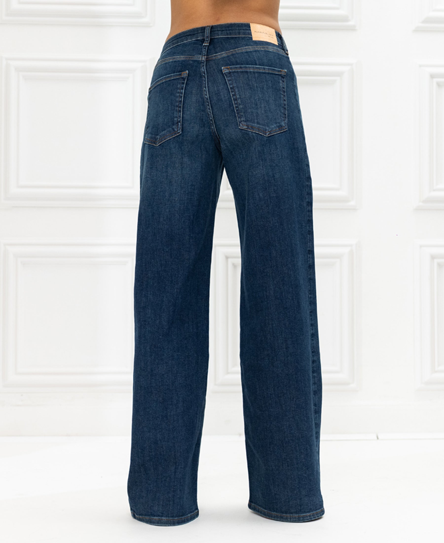 Wide leg blue heritage jeans, shown from the back against white panels.