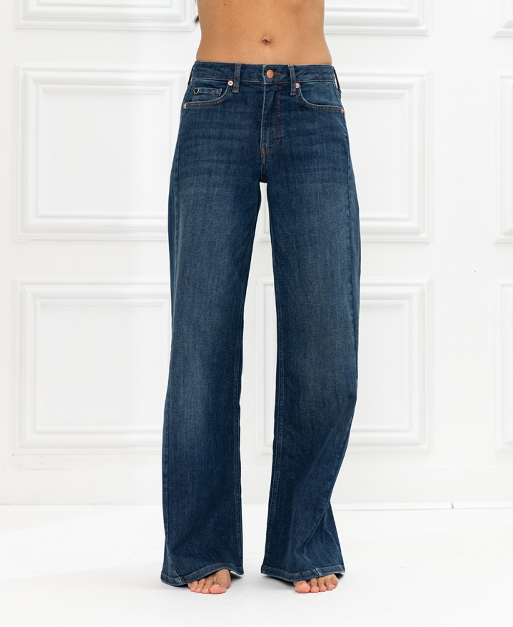 Wide leg jeans in blue heritage, made of organic cotton, shown against a white paneled wall.