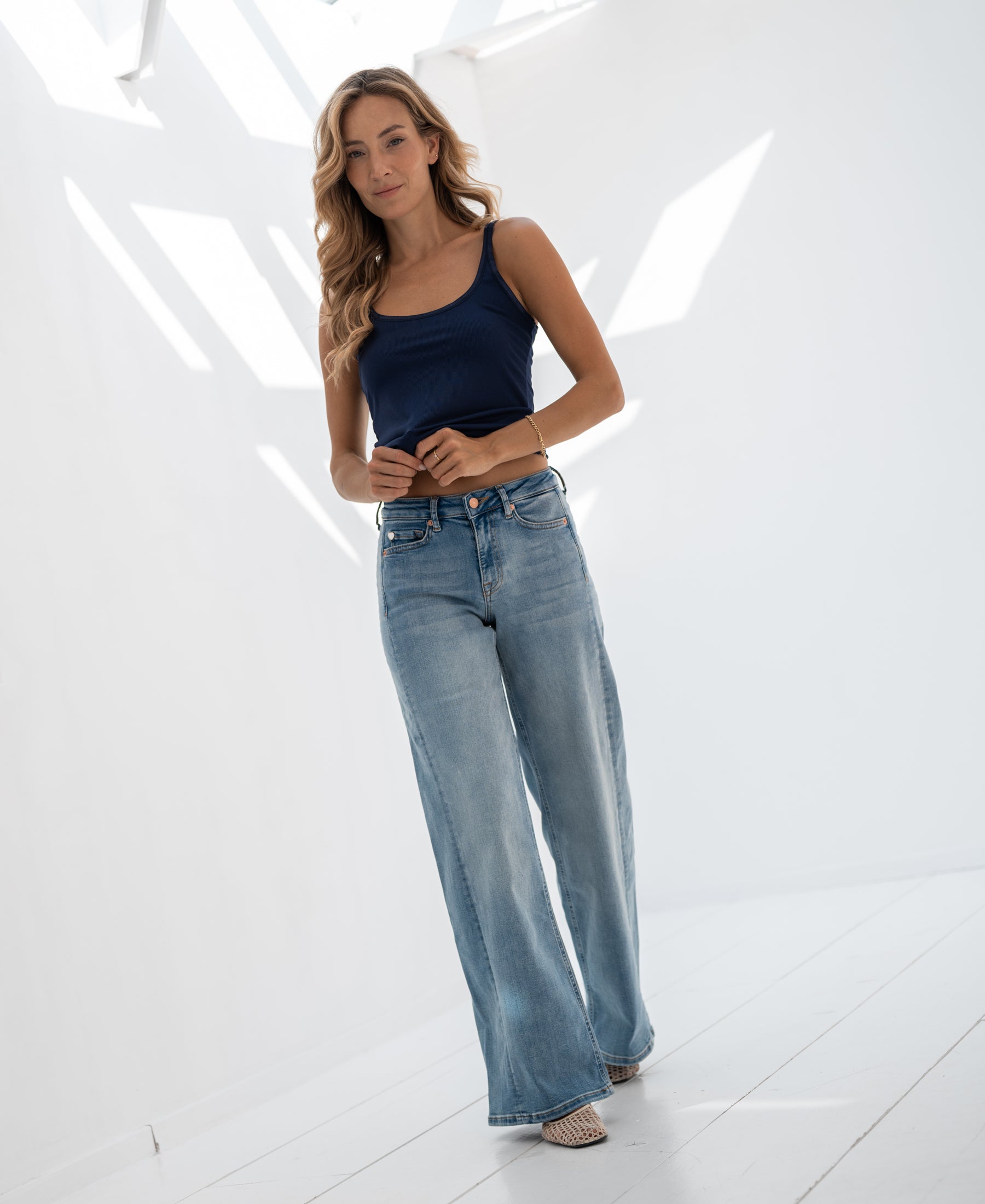 Wide leg jeans in light stone wash denim, shown in a sunlit room.
