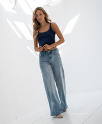 Wide leg jeans in light stone wash denim, shown in a sunlit room.