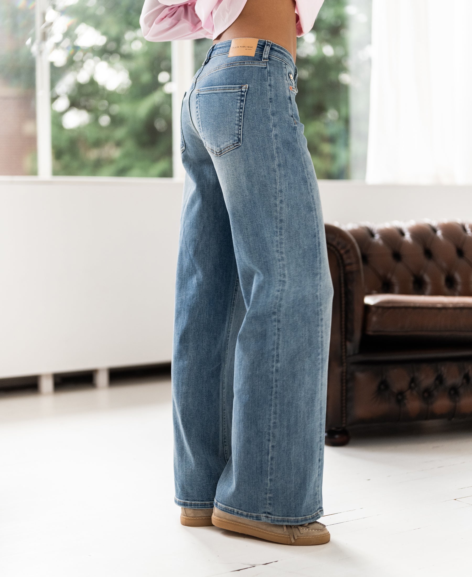 Wide leg jeans in light stone wash displayed indoors.