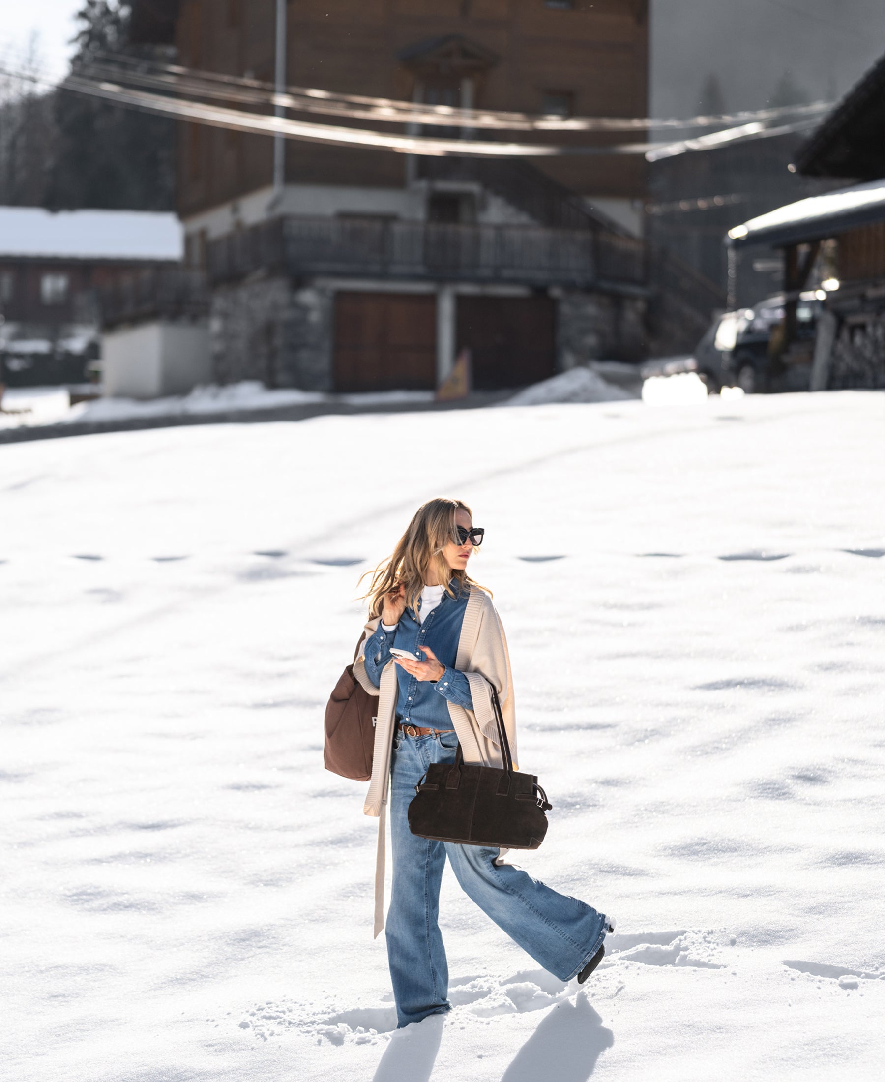 Woman in snow wearing a Tencel denim blouse; wooden houses in the background.
