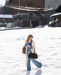 Woman in snow wearing a Tencel denim blouse; wooden houses in the background.