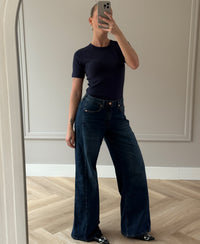 Wide leg blue heritage jeans in a mirror selfie, shown in a minimal room.