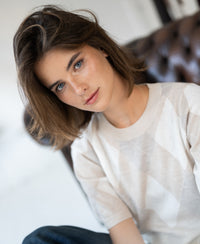 Woman wears the Argyle merino wool sweater LE STANFORD in sand melange by PLEIN PUBLIQUE.
