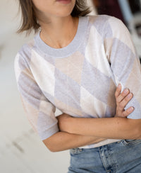 Argyle merino wool sweater in light grey melange, shown with model standing arms crossed.
