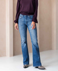 A person wears blue flared stonewash jeans indoors.