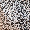 Close-up view of leopard print fabric with black and brown spots on a light tan background.
