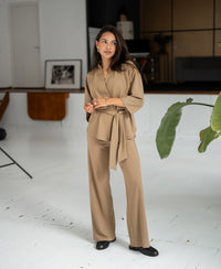Woman wearing the LA TOKYO dark sand kimono wrap vest stands, gazing to the side.