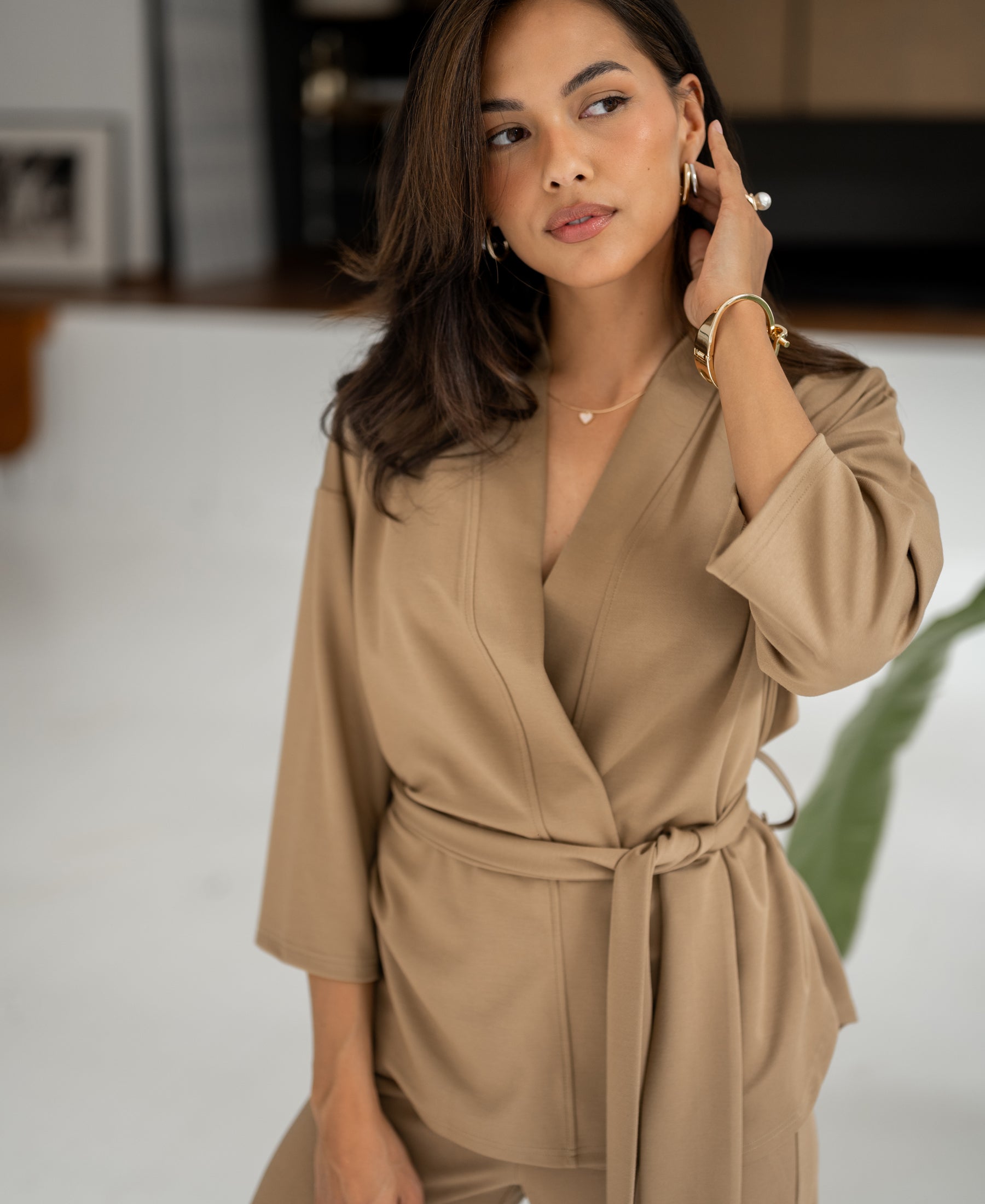Dark sand-colored kimono wrap vest is shown indoors, viewed from the side.
